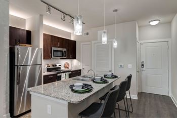 A kitchen with a refrigerator, microwave, and a dining table with chairs.